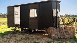 A modern, single-story mobile home with a sliding door, a small window, and a solar panel on the roof.