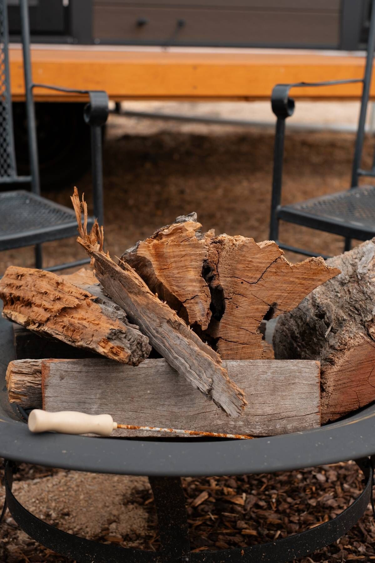 A round metal fire pit with logs and a white handle.