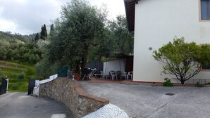 A building with a stone wall, outdoor seating, and a tree in the background. - Ferienhaus mit Meerblick, Terrasse, Wlan, Parkplatz (Toscana)