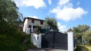 A gated entrance to a building with a white facade, a black gate, and a stone pillar. - Ferienhaus mit Meerblick, Terrasse, Wlan, Parkplatz (Toscana)