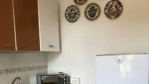 A kitchen with wooden cabinets, a sink, a microwave, and a refrigerator. - Ferienhaus mit Meerblick, Terrasse, Wlan, Parkplatz (Toscana)