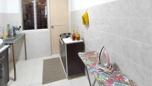 A compact kitchen with a small dining area, a window, and a door leading to a storage room.