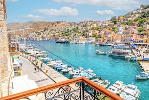 A coastal town with a marina, stone buildings, and a hillside. - Athenas - Neoclassic Harbour View (Symi)