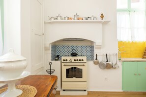 Een keuken met een witte kookplaat, een blauwe betegelde achterwand en een groen kastje.