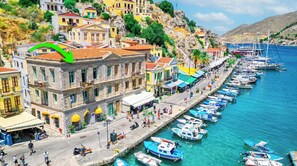 A coastal town with a row of colorful buildings, a marina with boats, and a clear blue sea. - Athenas - Neoclassic Harbour View (Symi)