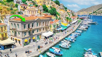 Un pueblo costero con una hilera de edificios coloridos, un puerto deportivo con barcos y un mar azul cristalino.