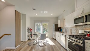 Una cocina moderna con armarios blancos, una estufa de acero inoxidable y un ventanal que proporciona luz natural.