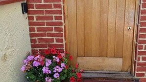 A wooden door with a small window, a brick wall, and a potted plant with flowers. - Fab Studio Room in Botley, Oxford (Oxford)