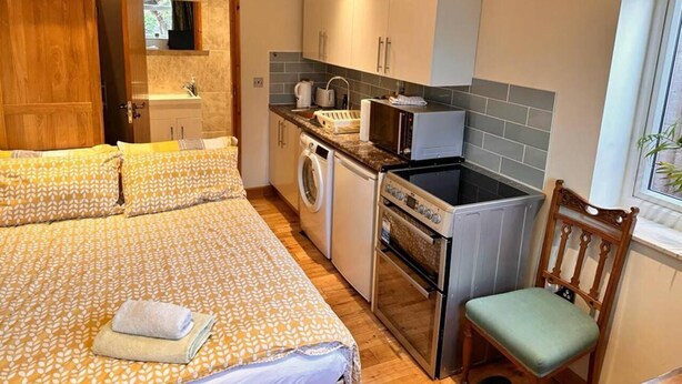 A compact room with a bed, a washing machine, a small kitchen with a sink and stove, and a window with a view. - Fab Studio Room in Botley, Oxford (Oxford)