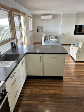 Een moderne keuken met een centraal eiland, witte kasten en een houten vloer.
