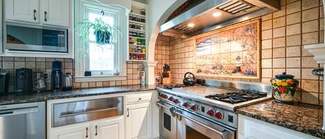 A modern kitchen with white cabinets, stainless steel appliances, and a tiled backsplash.