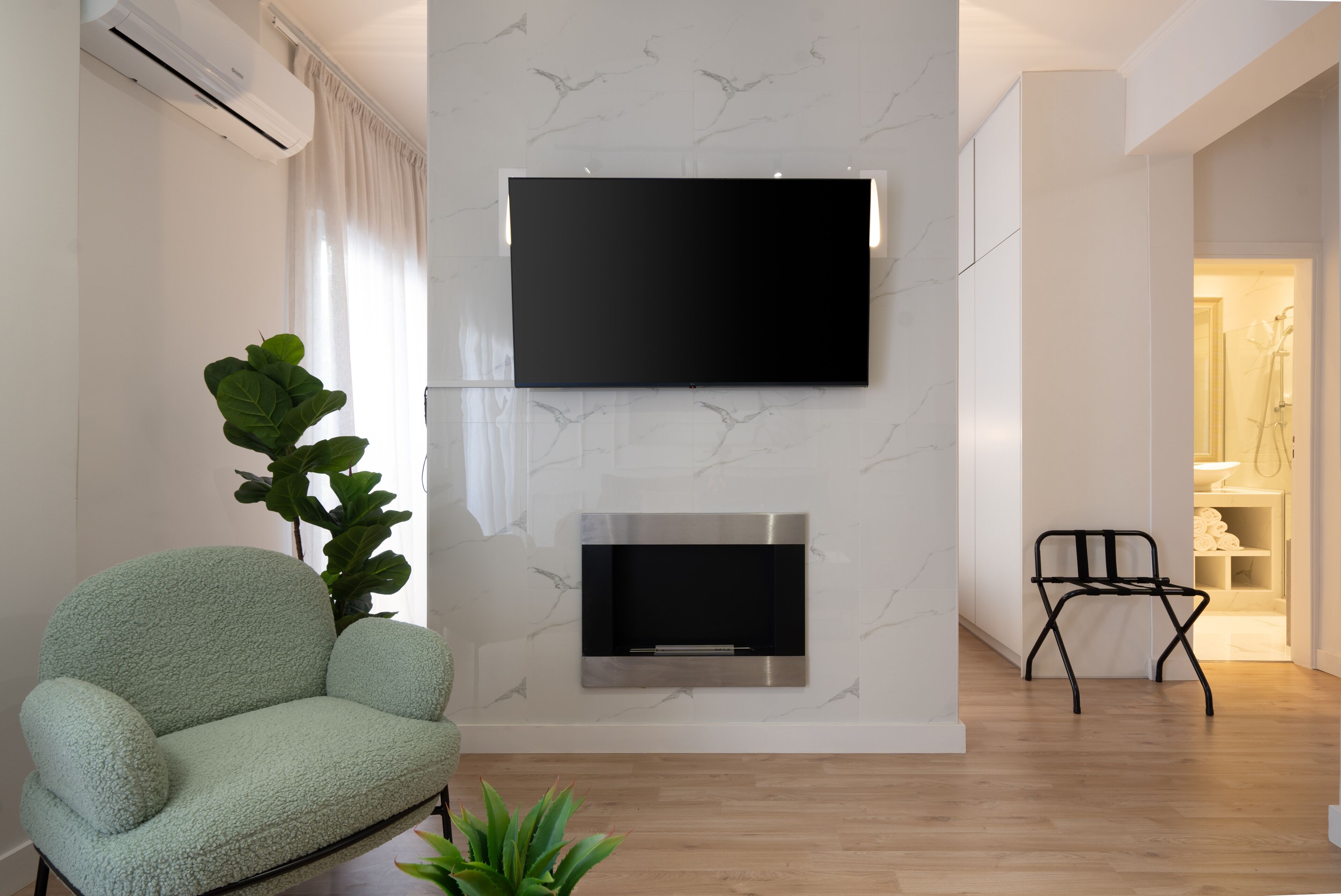 Un soggiorno moderno con TV a parete, un divano, una pianta e un camino.