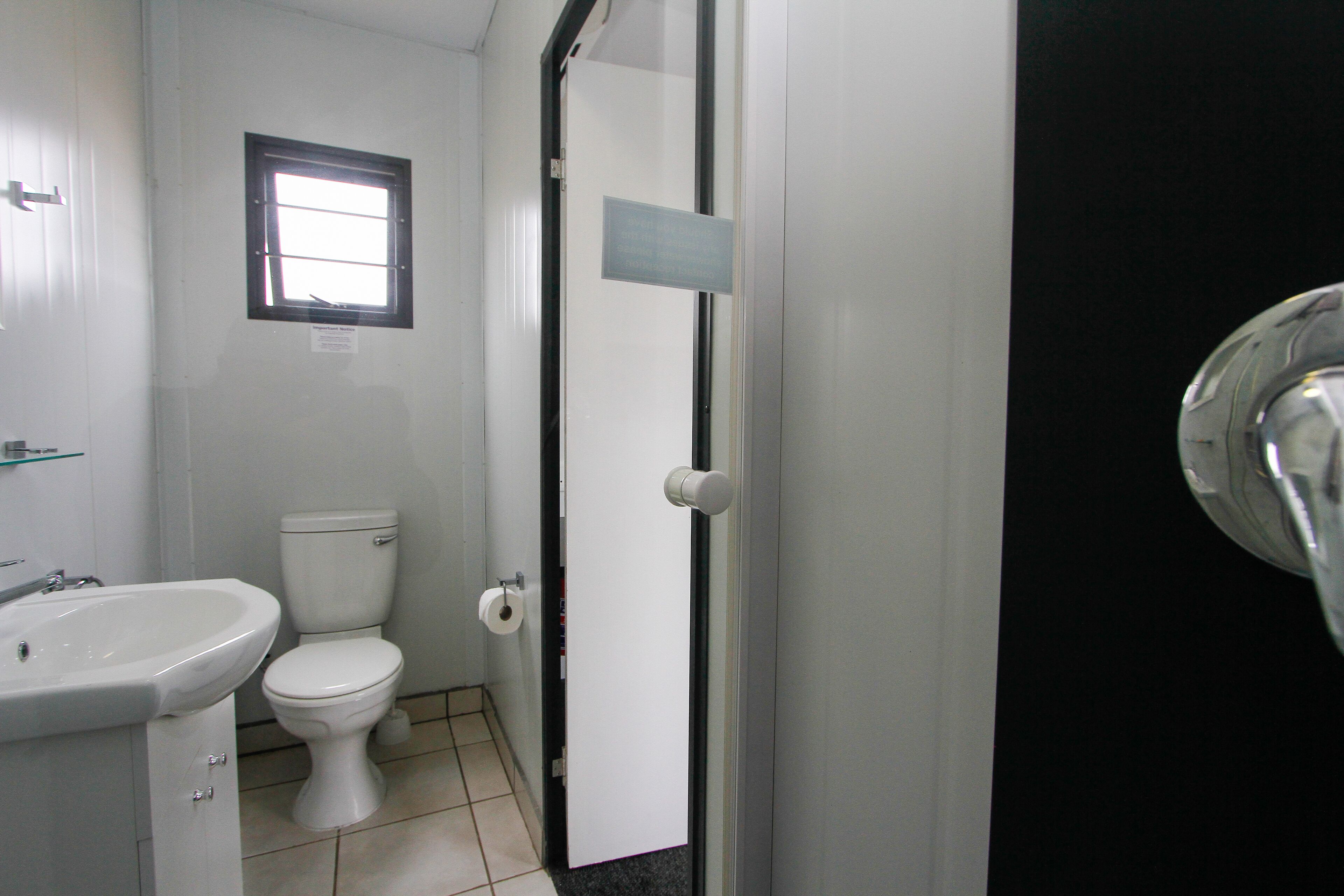 Et badeværelse med toilet, håndvask og et vindue.