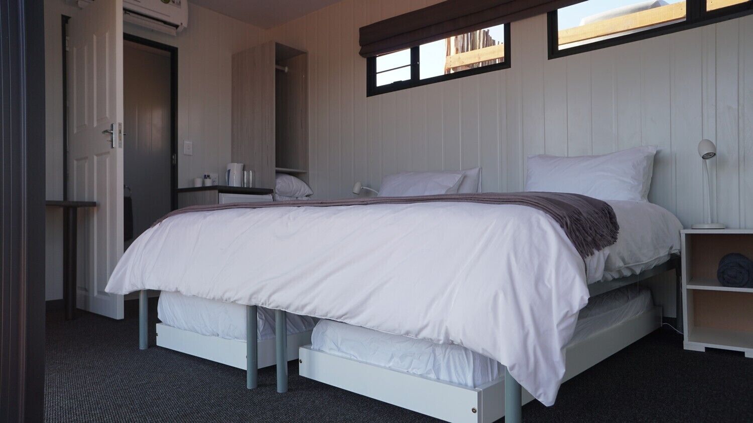 Un dormitorio con cama, mesita de noche, estante y armario.