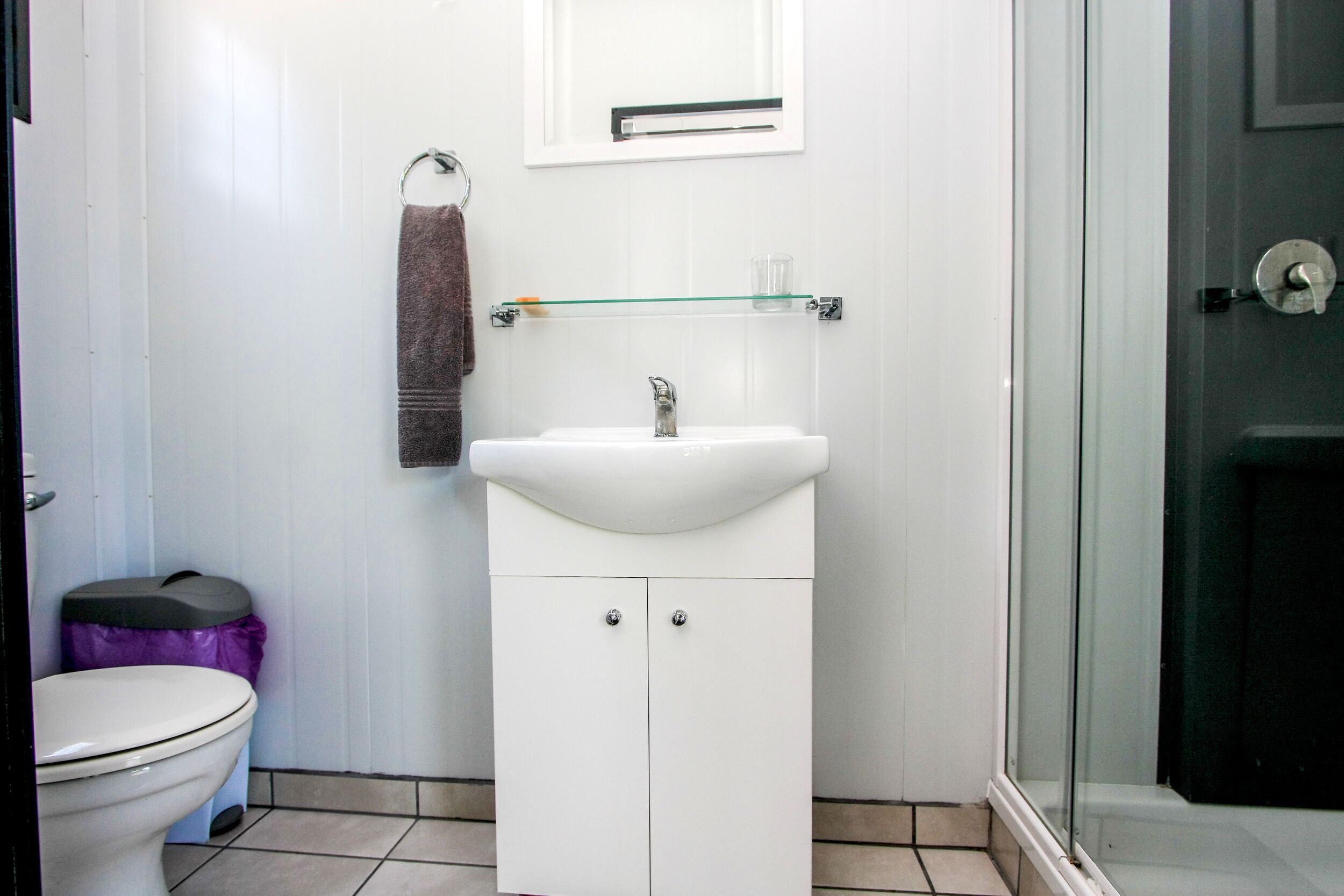 Un baño con lavamanos blanco, inodoro y cabina de ducha de vidrio.