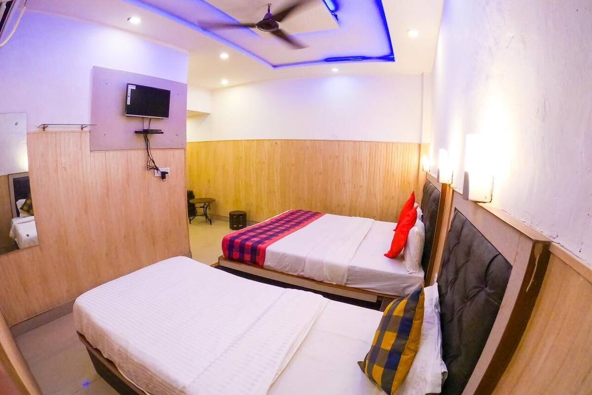 Une chambre d’hôtel avec deux lits, un ventilateur de plafond, un téléviseur fixé au mur et un mur recouvert de panneaux en bois.