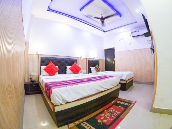A hotel room with a large bed, a ceiling fan, and a TV mounted on the wall. - Green house Homestay (Agra)