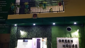 Um edifício de dois andares com fachada verde e uma placa que diz "GREEN HOUSE".