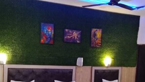 Quarto de hotel com duas camas, parede verde com textura e iluminação no teto.