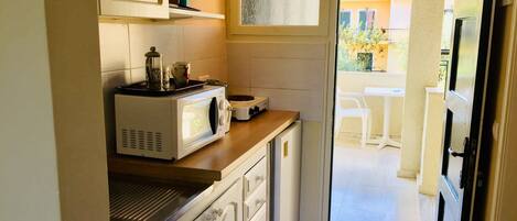 A compact kitchen with a microwave, coffee maker, and a small window.
