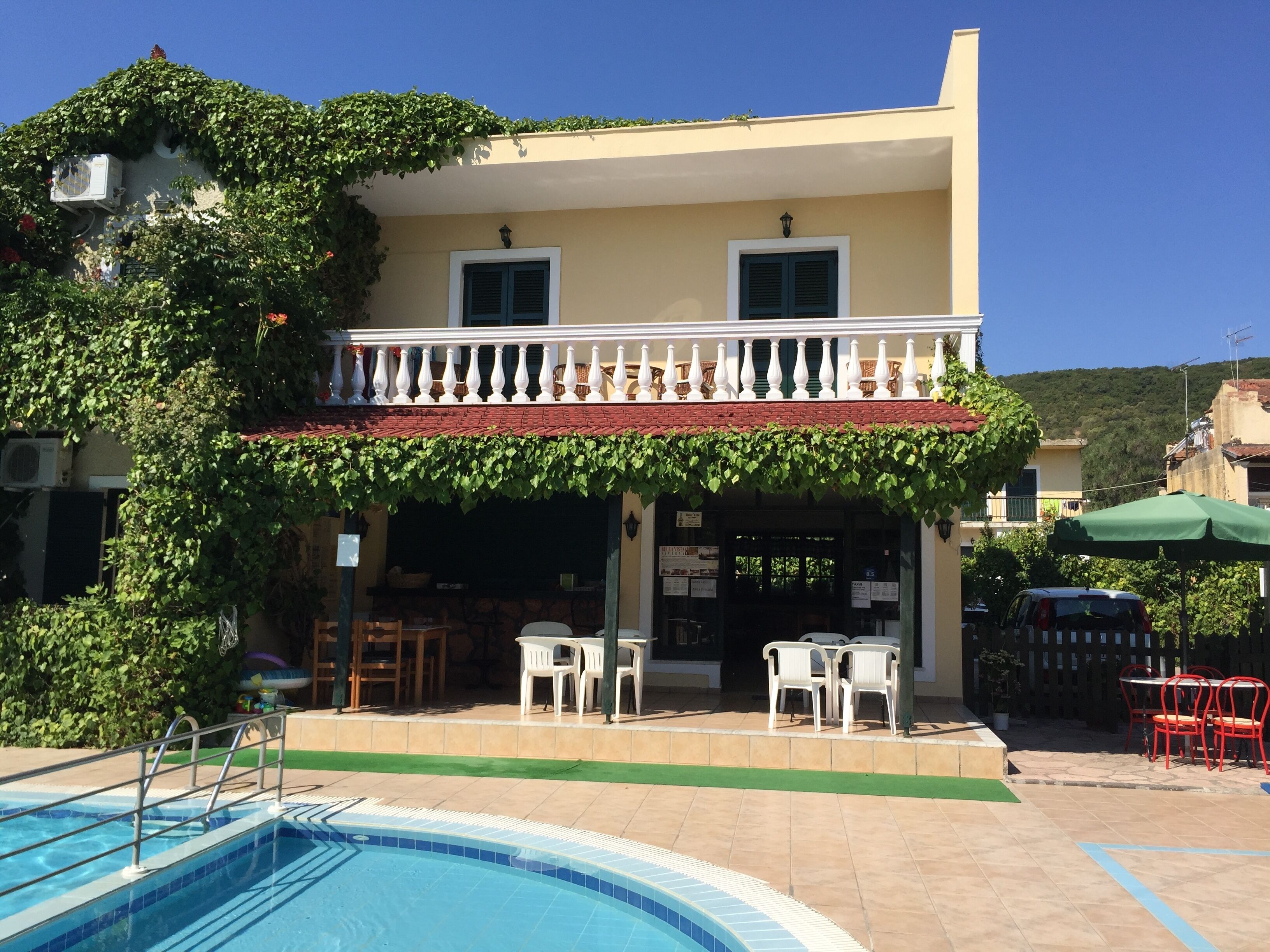 A building with a pool, outdoor seating, and a covered patio area.