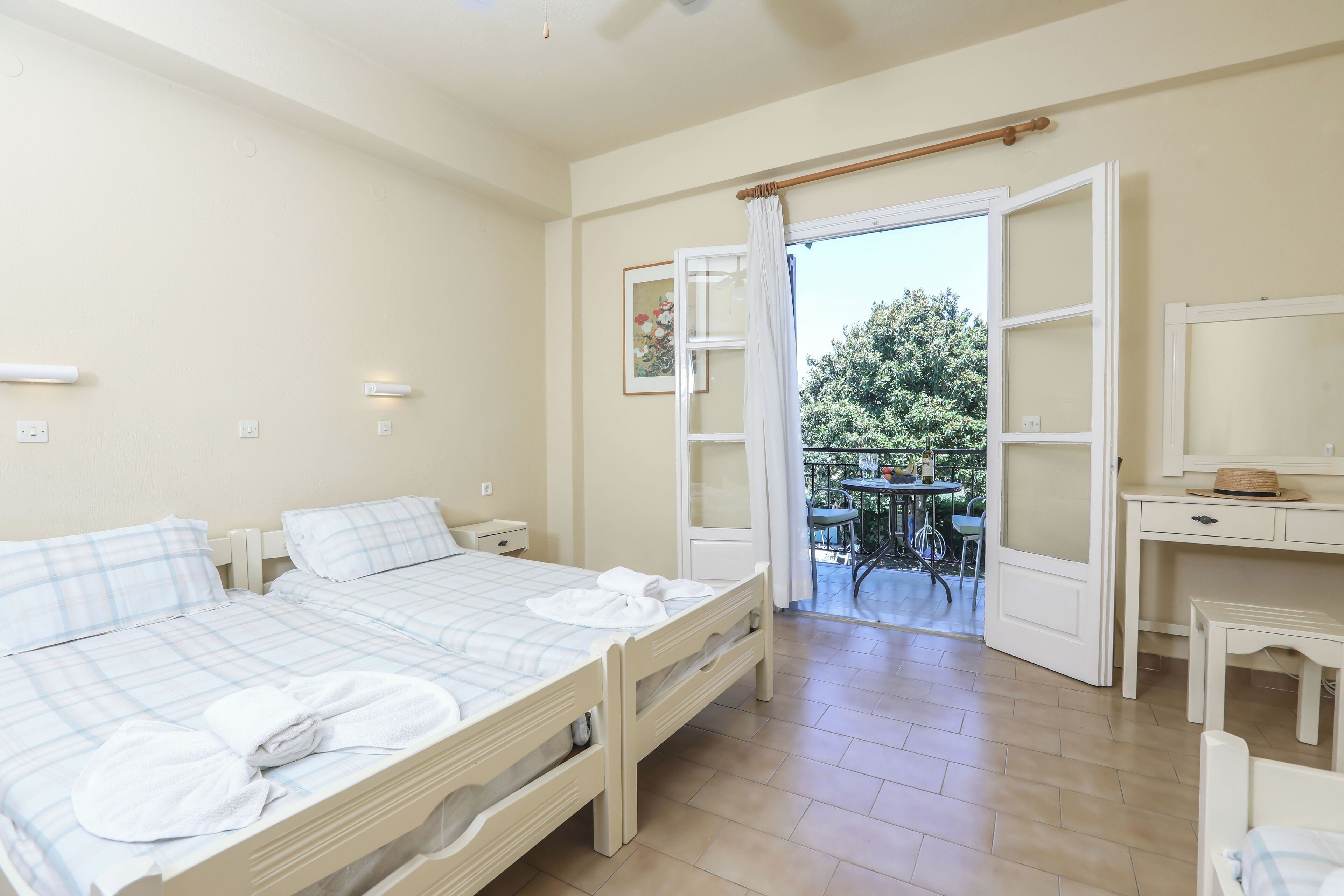 Un dormitorio con dos camas, un escritorio y un balcón con una mesa y sillas.
