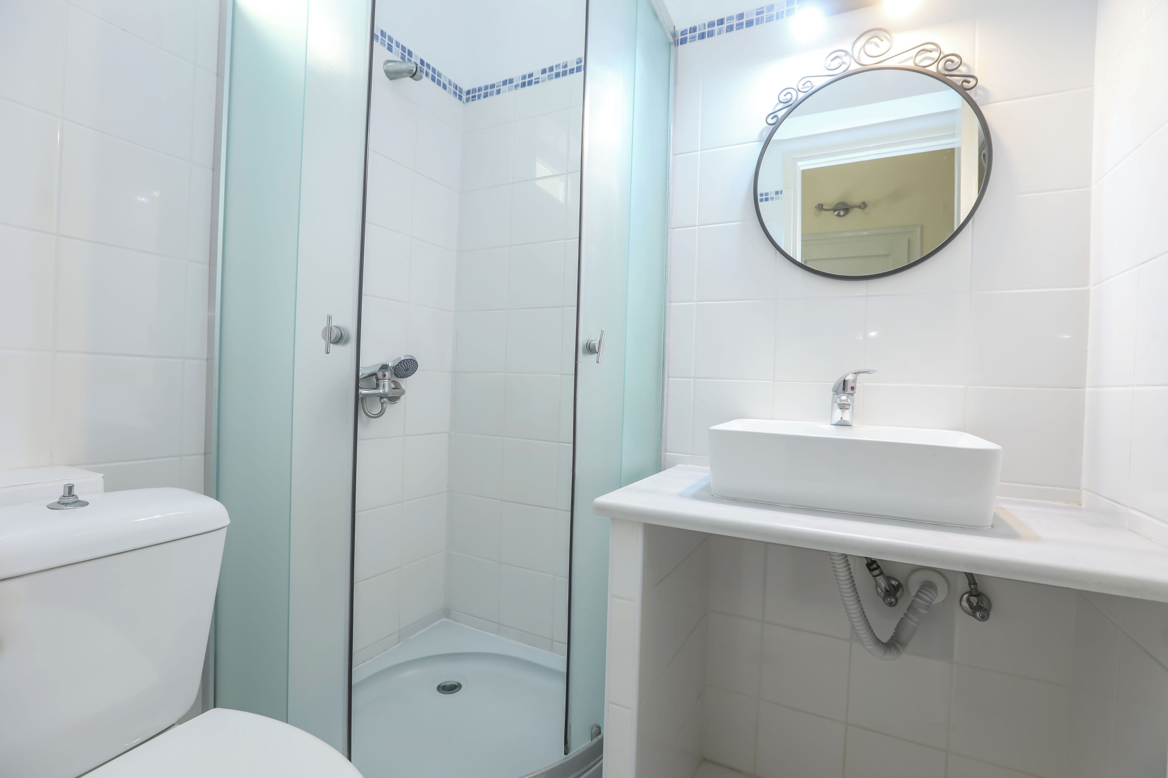 A bathroom with a glass-enclosed shower, a toilet, and a sink with a mirror above it.