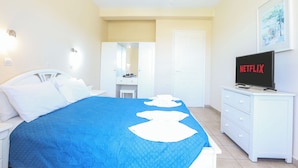 Habitación de hotel con cama, televisión, cómoda y puerta que da a un baño.