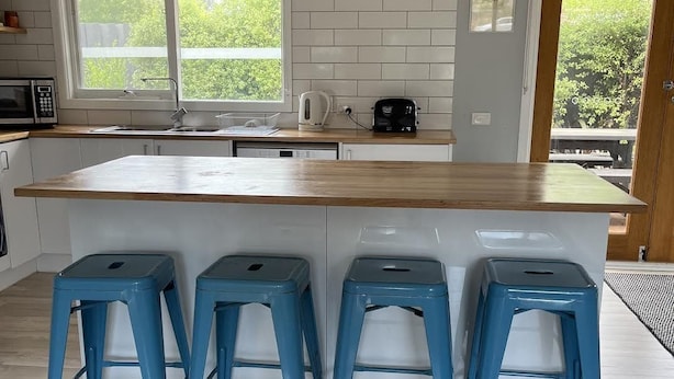 A kitchen with a large island, four blue stools, a microwave, a kettle, and a toaster. - Ronny's Tootgarook. (Tootgarook)