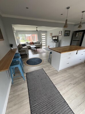 Une cuisine moderne avec un plan de travail en bois, un coin repas avec un canapé et une vue sur l’extérieur.
