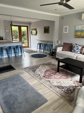 Ein modernes Wohnzimmer mit einer Couch, einem Couchtisch und blauen Barhocker.