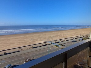 Vista sulla spiaggia dal balcone, con un parcheggio e una strada in primo piano.