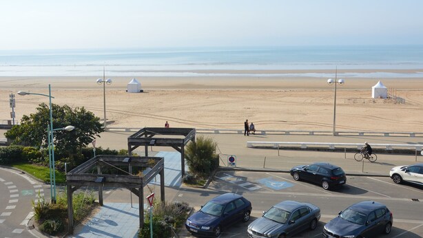 A beachside parking area with cars, a pedestrian walkway, and a view of the beach. - Comfortable Studio for 3 in Saint Jean de Monts, Near Beach (Saint-Jean-de-Monts)