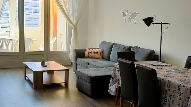 A modern living room with a grey sofa, a wooden coffee table, and a dining table with chairs. - Spacious apartment for 4, 200m from the beach, private parking included (Saint-Hilaire-de-Riez)