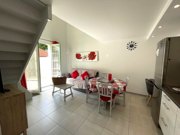 A modern kitchen with white cabinets, a dining table with red and white checkered tablecloth, and a staircase leading to an upper level.