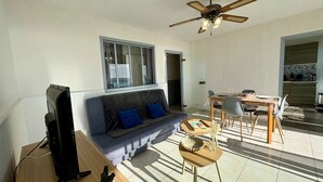 A living room with a sofa, a dining table, and a ceiling fan. - Bright studio with alcove, sea-view balcony, private parking (Saint-Jean-de-Monts)