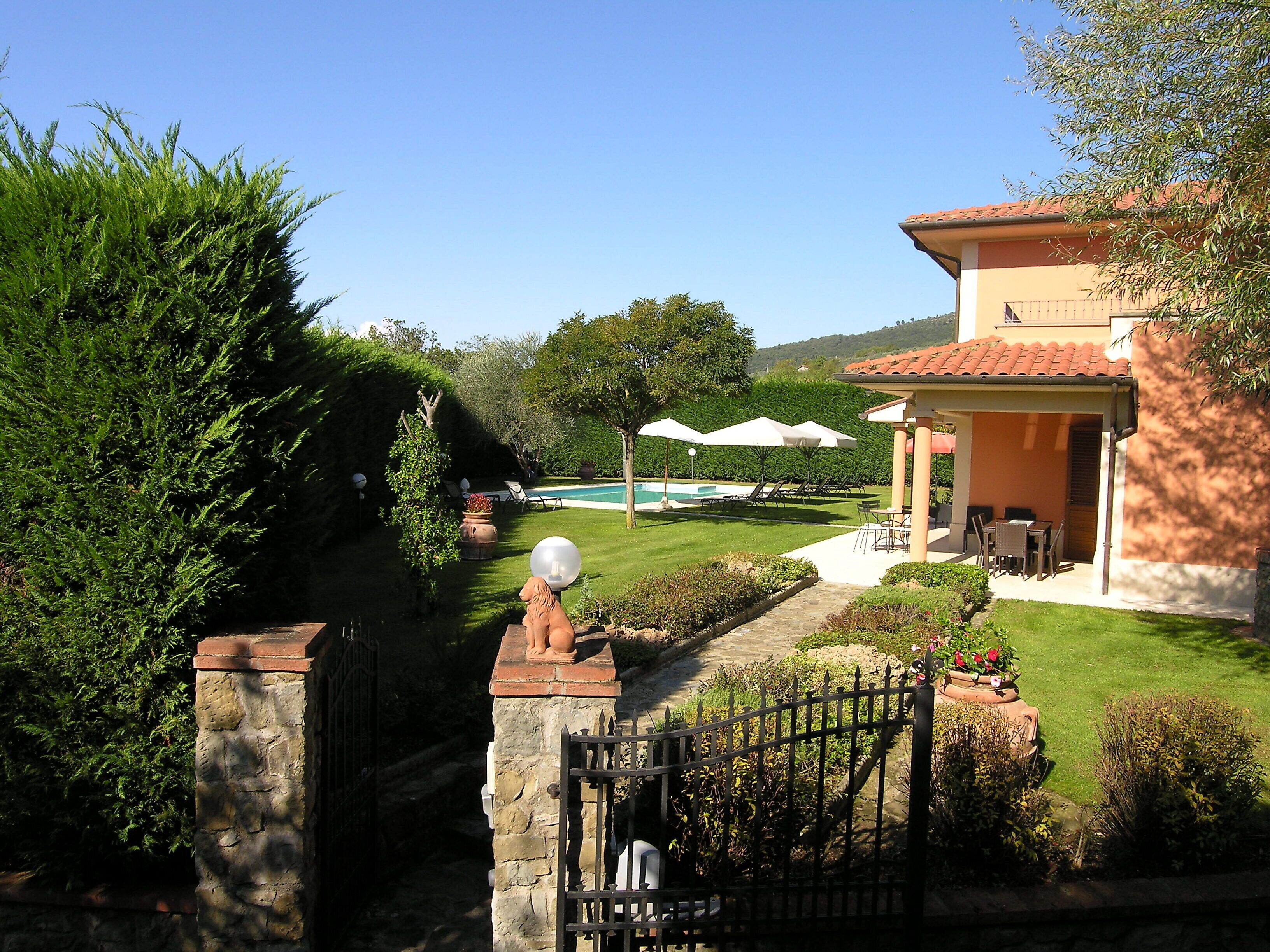 Ein gepflegter Garten mit Pool, Sitzgelegenheiten im Freien und einem Steintor.