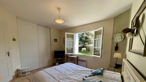 A bedroom with a bed, a television, a window, and a chair. - Spacious House with Garden, Terrace, Near Forest and Beach - Saint Jean de Monts (Saint-Jean-de-Monts)