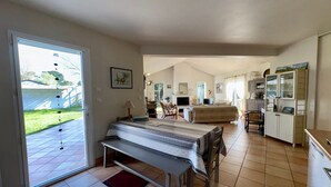 A spacious living area with a large bed, a dining table, and a kitchen area. - Spacious House with Garden, Terrace, Near Forest and Beach - Saint Jean de Monts (Saint-Jean-de-Monts)