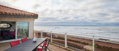 Un balcón con mesa y sillas que da al mar.