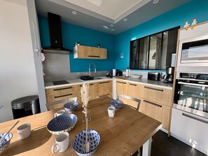 Una cocina moderna con una mesa de madera, cuencos blancos y azules estampados y un horno empotrado.