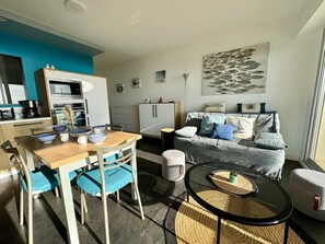 Una sala de estar moderna con comedor, un juego de sofá, una mesa de centro y una cocina al fondo.