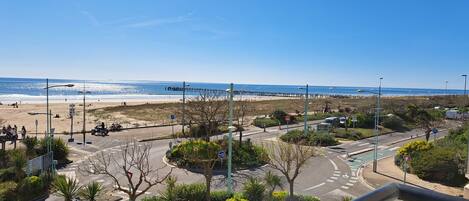 A coastal road with a roundabout, beach in the background, and a clear blue sky.