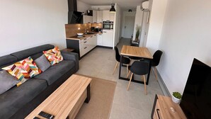 A modern apartment with a living room, dining area, and kitchen. - Beautiful T2 with large terrace and parking, near the sea (Valras-Plage)