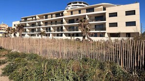 A multi-story hotel with a modern design, featuring balconies on each floor and a central circular structure. - Beautiful T2 with large terrace and parking, near the sea (Valras-Plage)