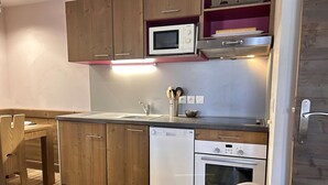 A compact kitchen with wooden cabinets, a microwave, a dishwasher, and an oven.