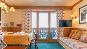 A cozy room with a dining table, chairs, a sofa, and a TV.