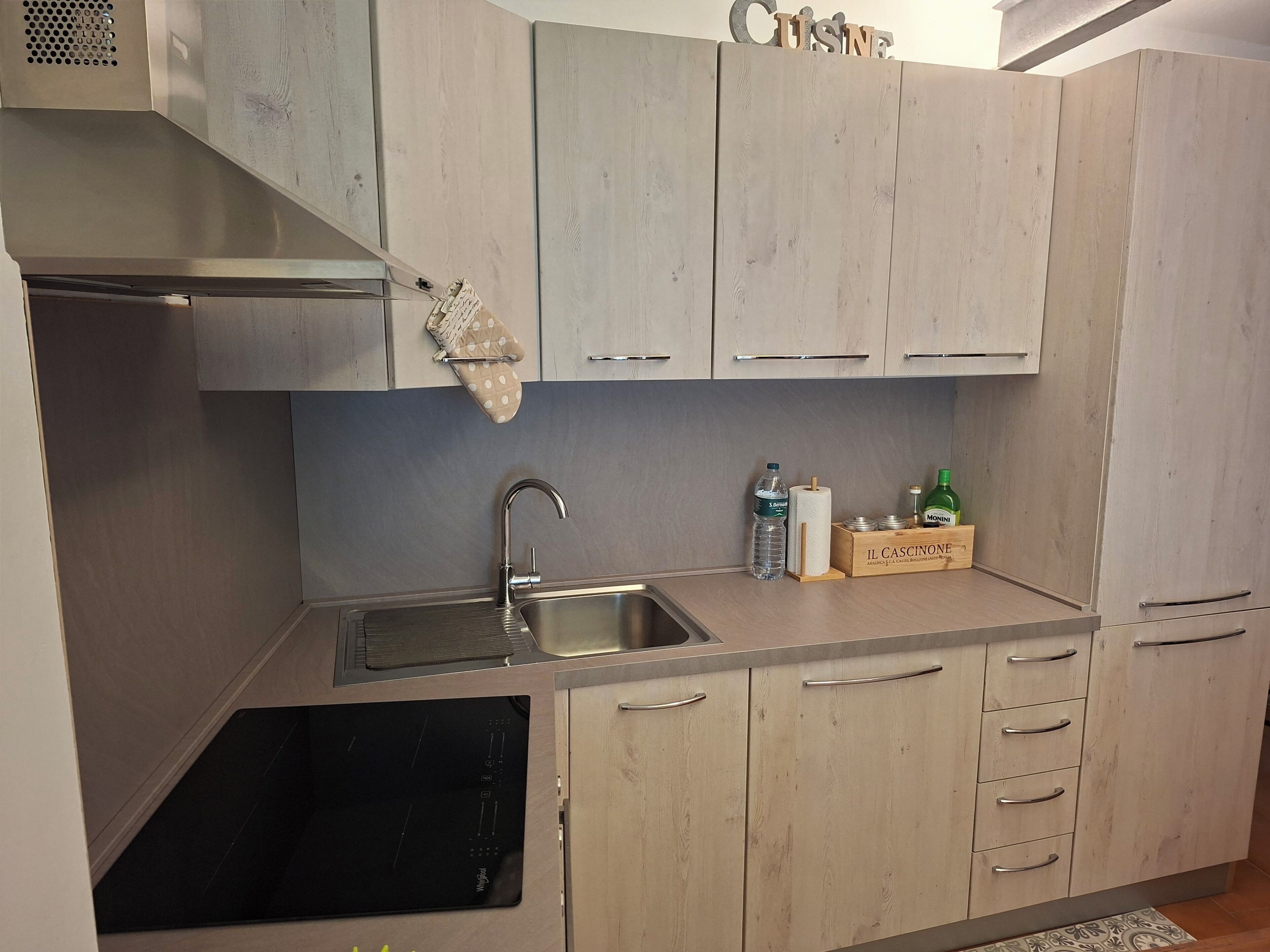 Een moderne keuken met een roestvrijstalen spoelbak, houten keukenkastjes en een inbouwoven.