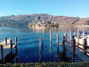 Un lac avec une jetée en bois et un bateau. Au loin, on aperçoit une ville avec des bâtiments situés sur une colline.
