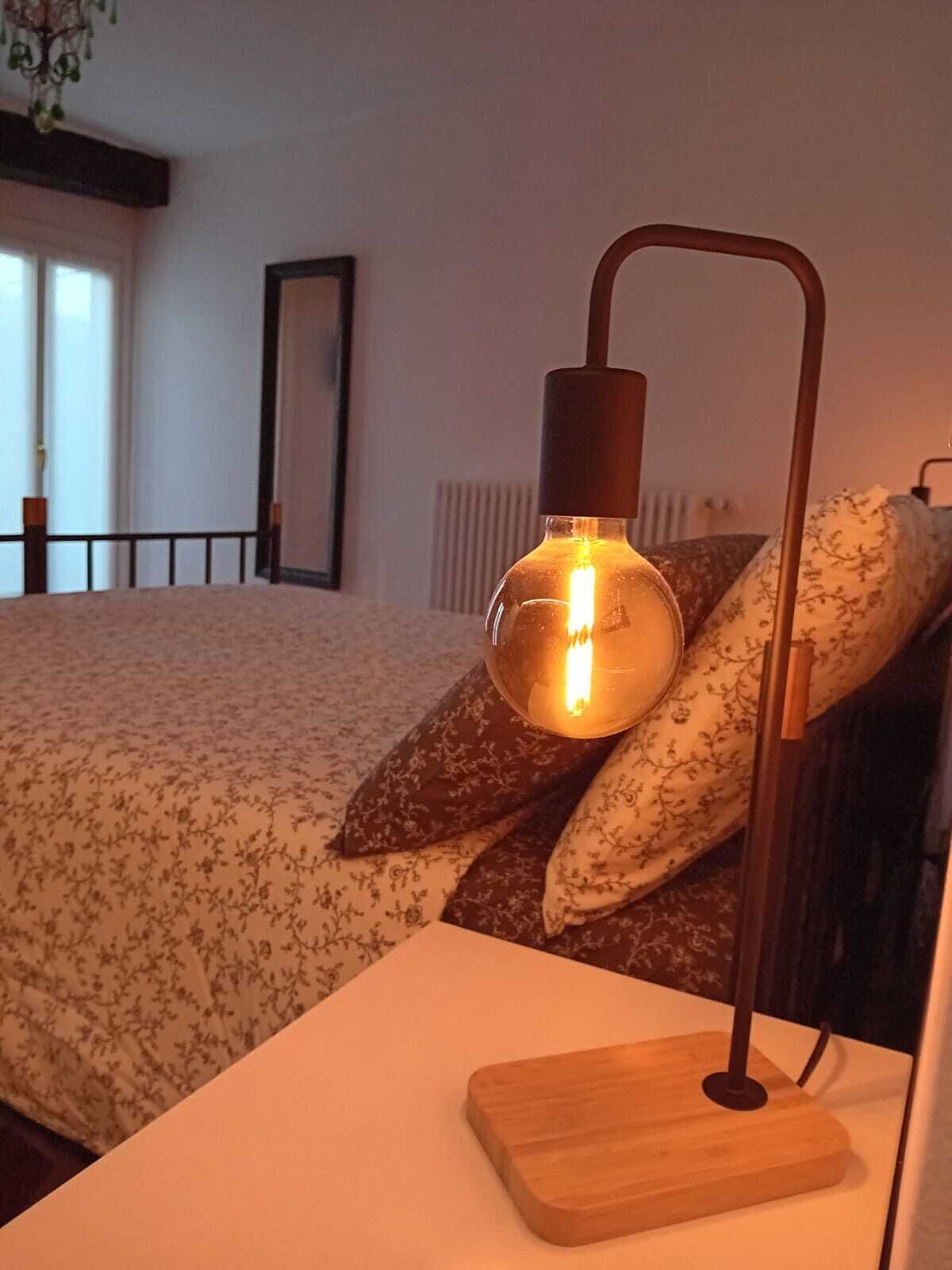 A bed with floral bedding, a bedside lamp, and a wooden nightstand.